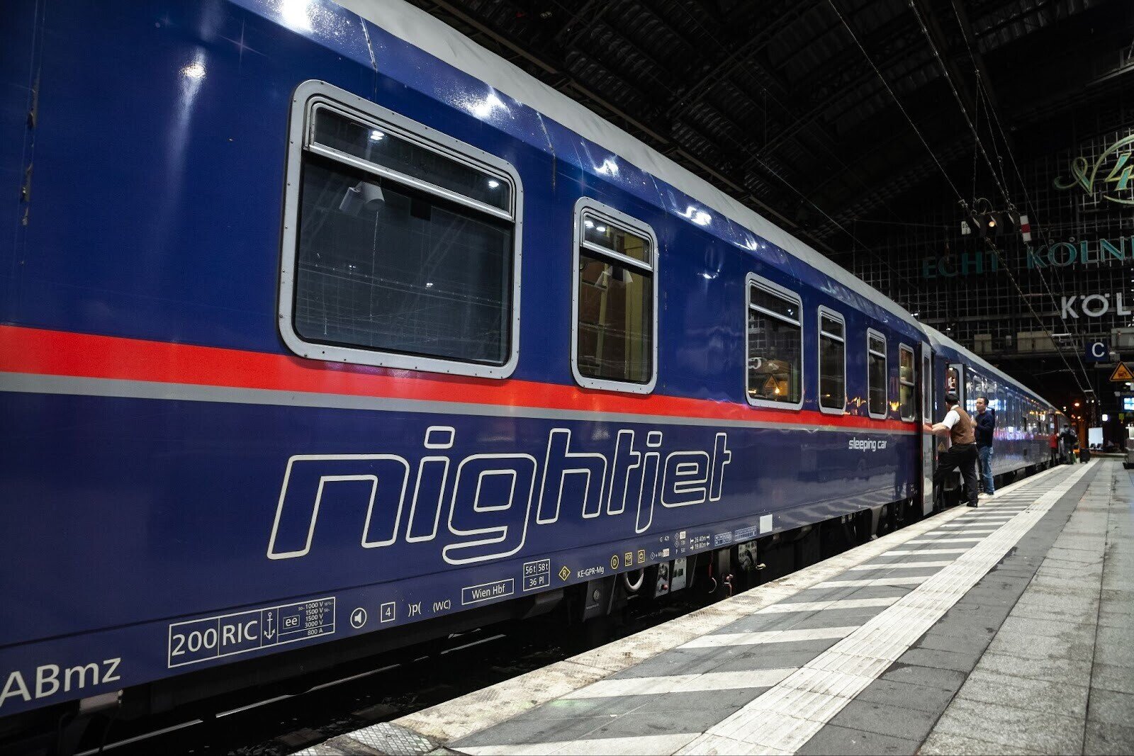 ÖBB Nightjet sleeper train ready for departure from Cologne train station in Germany with two people standing at the entrance