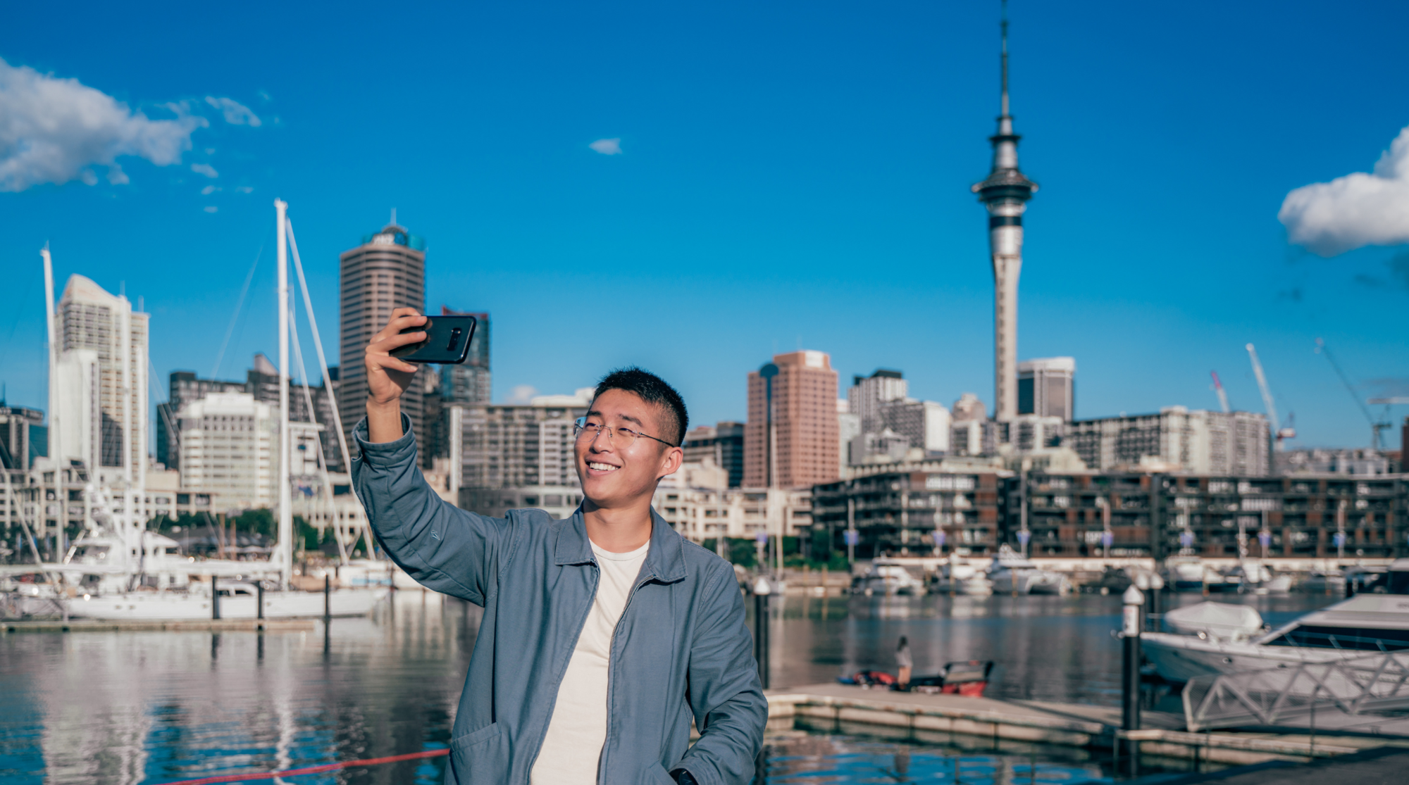 Ein Mann steht in Auckland in Neuseeland und benutzt seine SIM-Karte, um ein Foto zu schießen