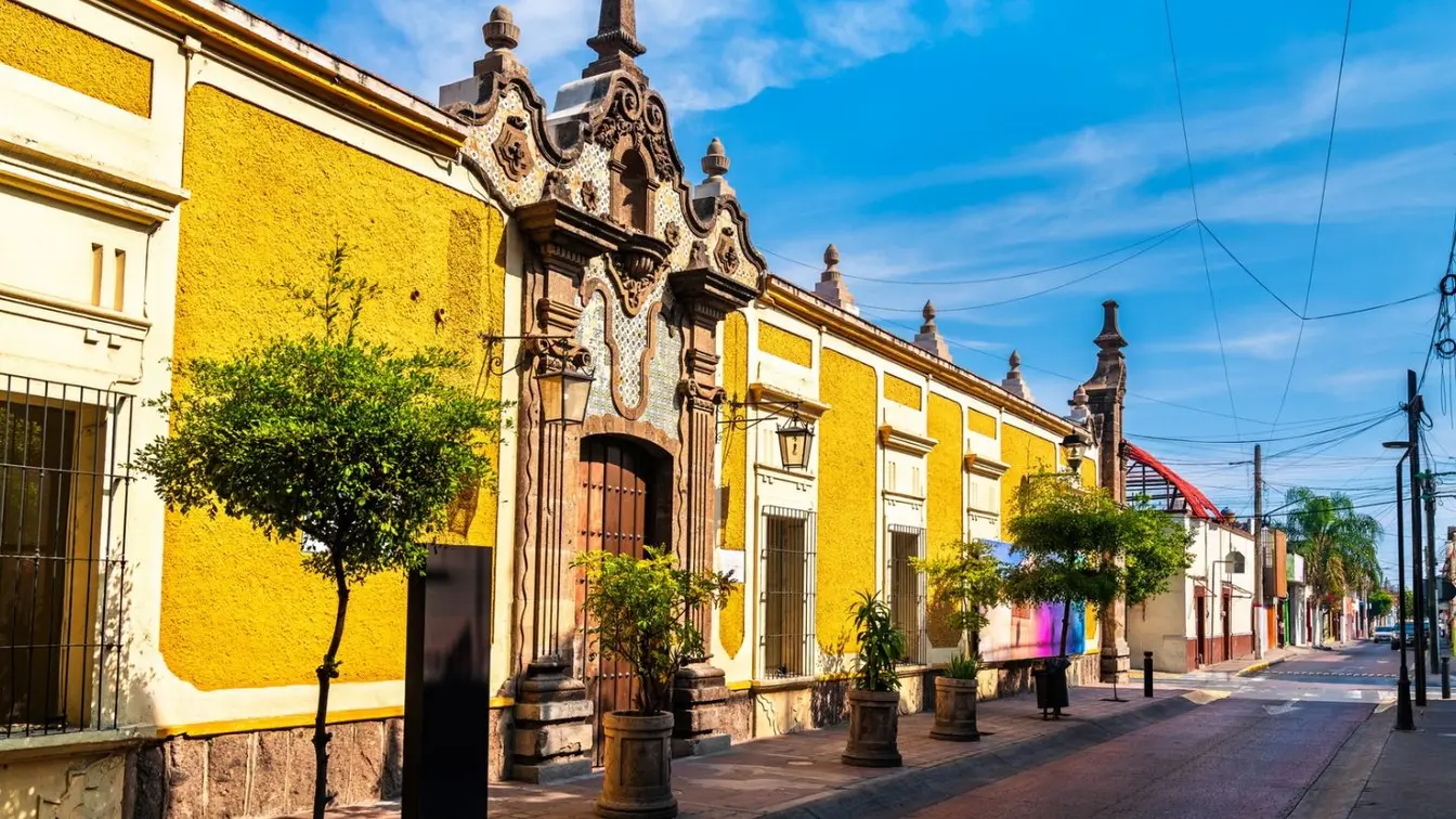 Fachadas tradicionales en Tlaquepaque, Guadalajara, en una calle tranquila con talleres y tiendas de artesanía.
