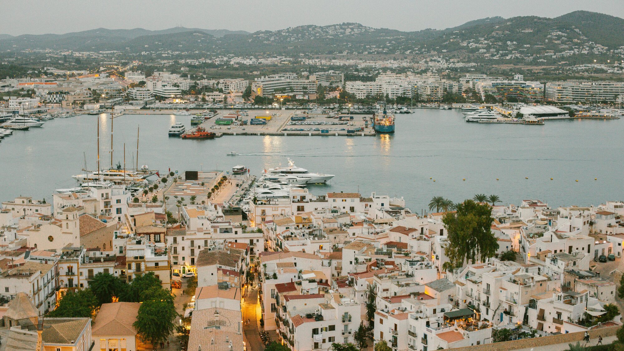 Hotels, yachts, and buildings with glowing windows along the Ibiza waterline