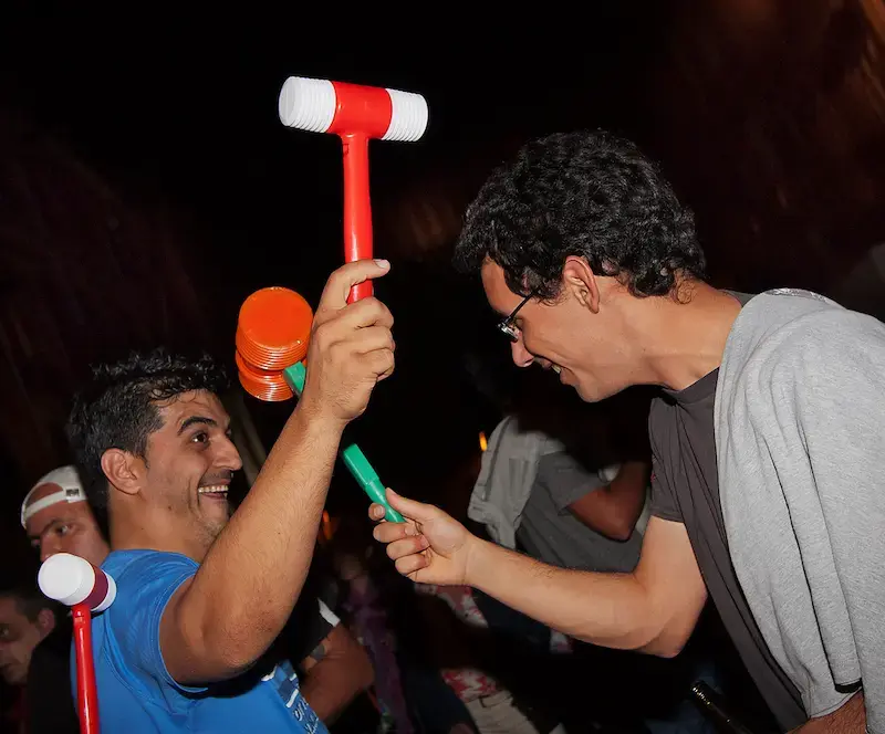 Deux fêtards se frappant gentiment avec des marteaux en plastique pendant la fête de la São João à Porto