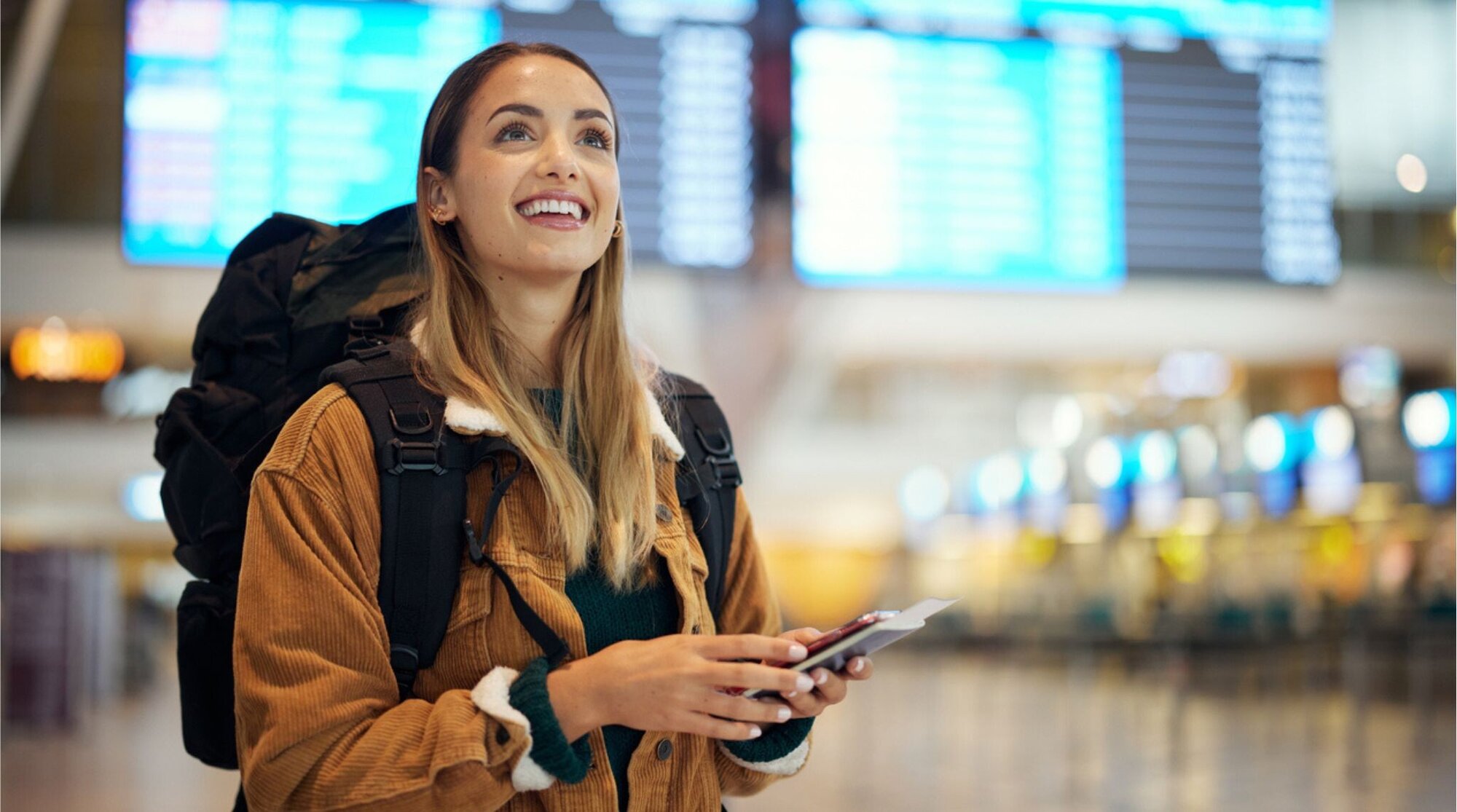 Mulher jovem usando celular no aeroporto com mochila nas costas