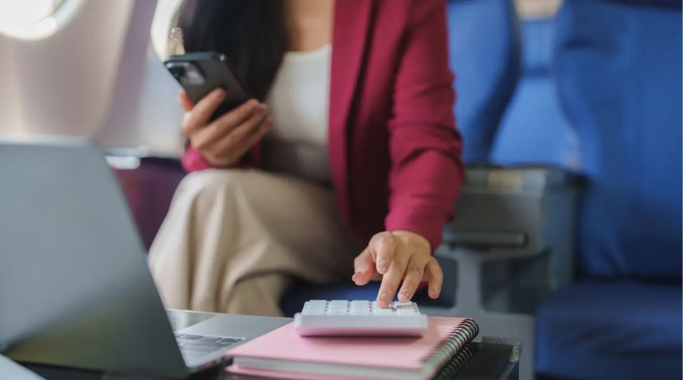 Viajante usando calculadora e smartphone durante o voo.