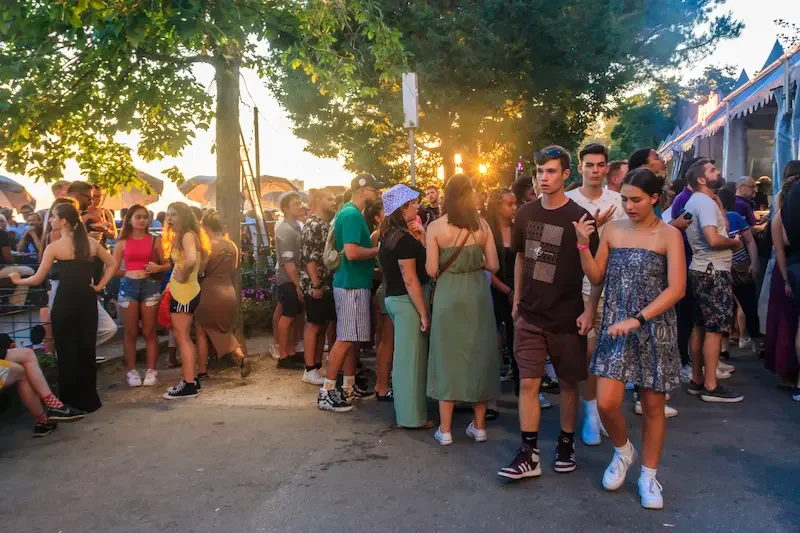 Foule de festivaliers se promenant entre les stands et les scènes extérieures du Montreux Jazz Festival au bord du lac Léman