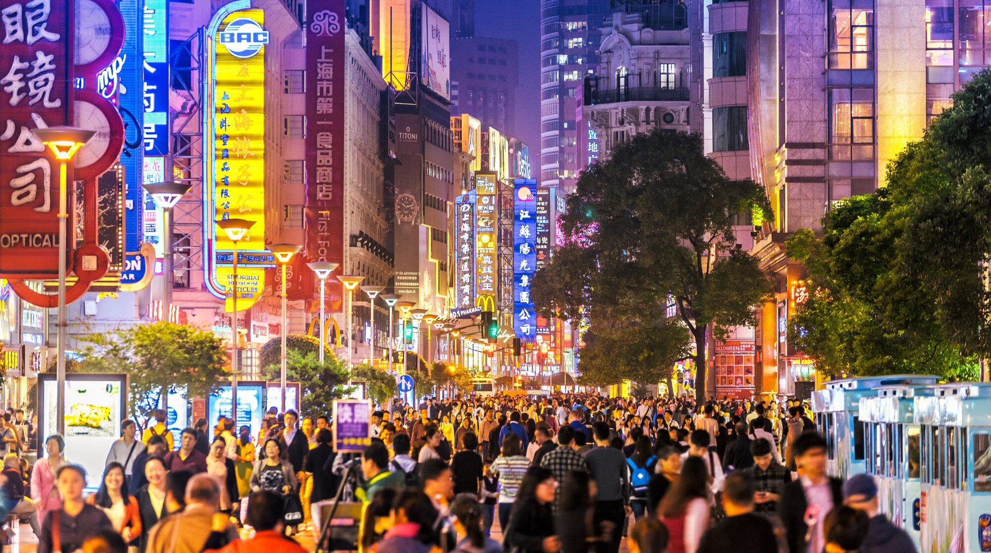 Ein belebter Markt in Shanghai bei Nacht mit bunten Lichtern