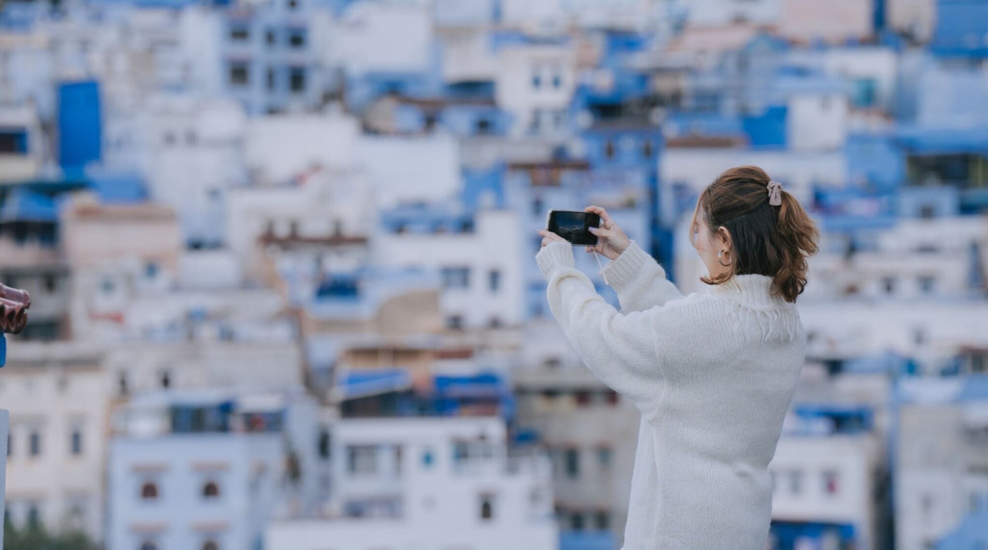touriste avec son telephone prenant une photo devant la ville bleue au Maroc