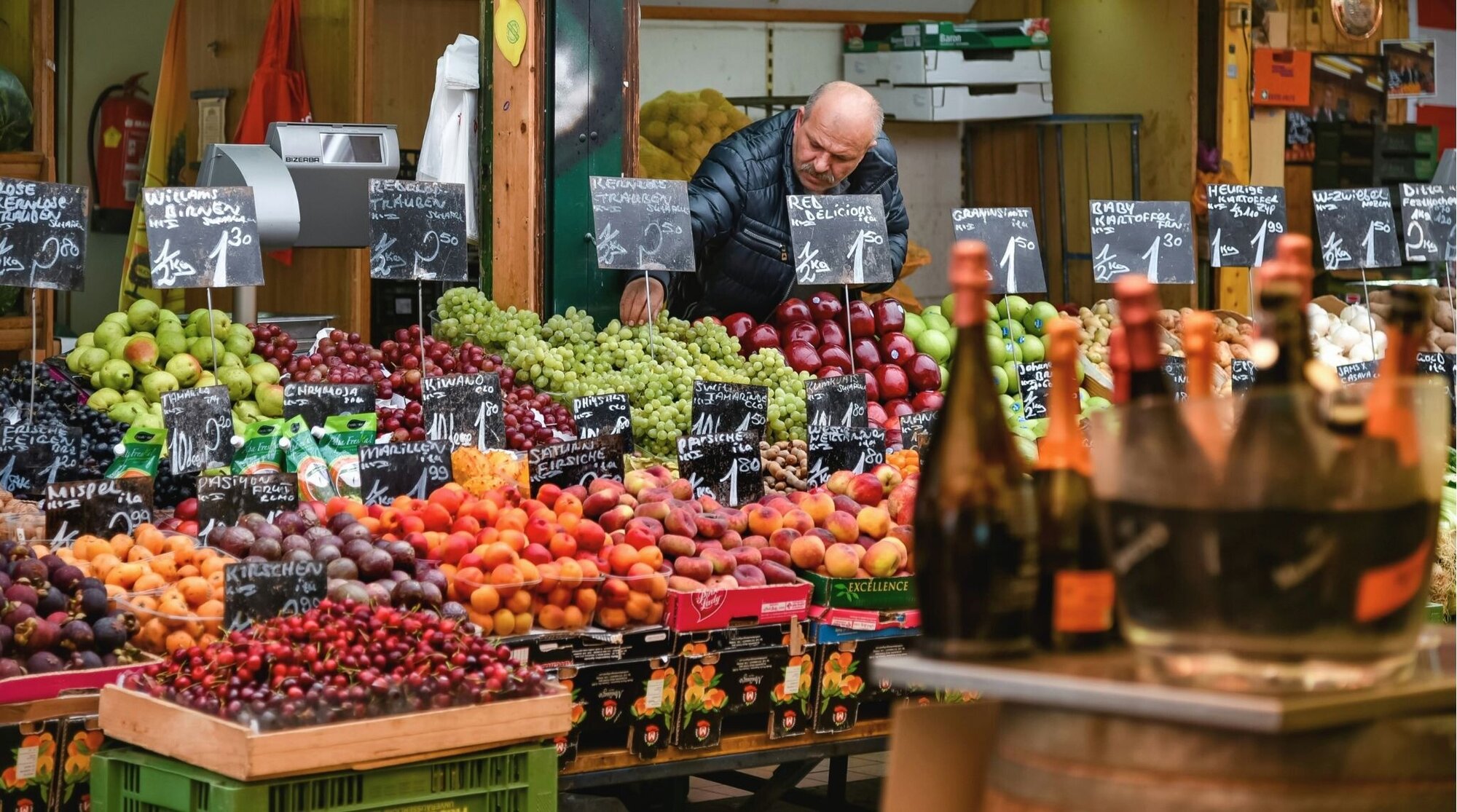 Vendedor ajustando frutas em banca de mercado.