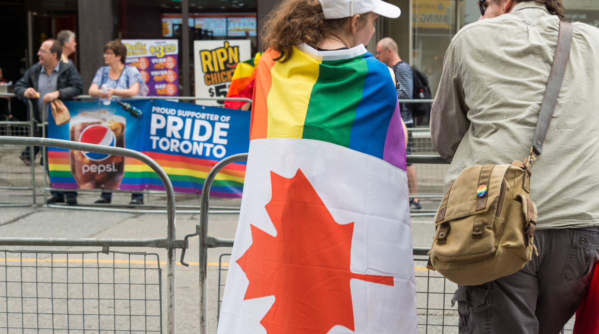 A woman with a Canadian Pride flag hung over her shoulders