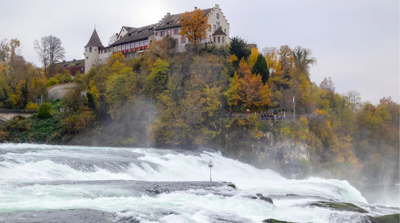 Vista da Rheinfall e de castelo em montanha em Schaffhausen.