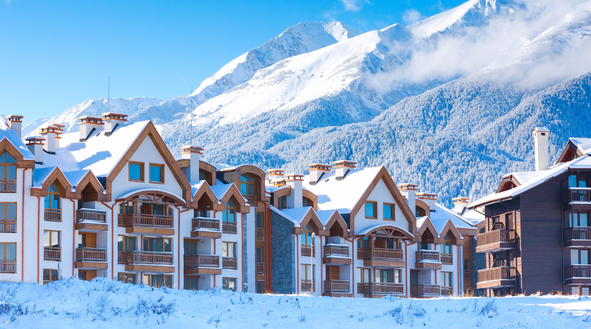 Panorama innevato della stazione sciistica di Bansko in Bulgaria, con case di montagna e piste da sci, meta ideale per sciare in Europa low cost.