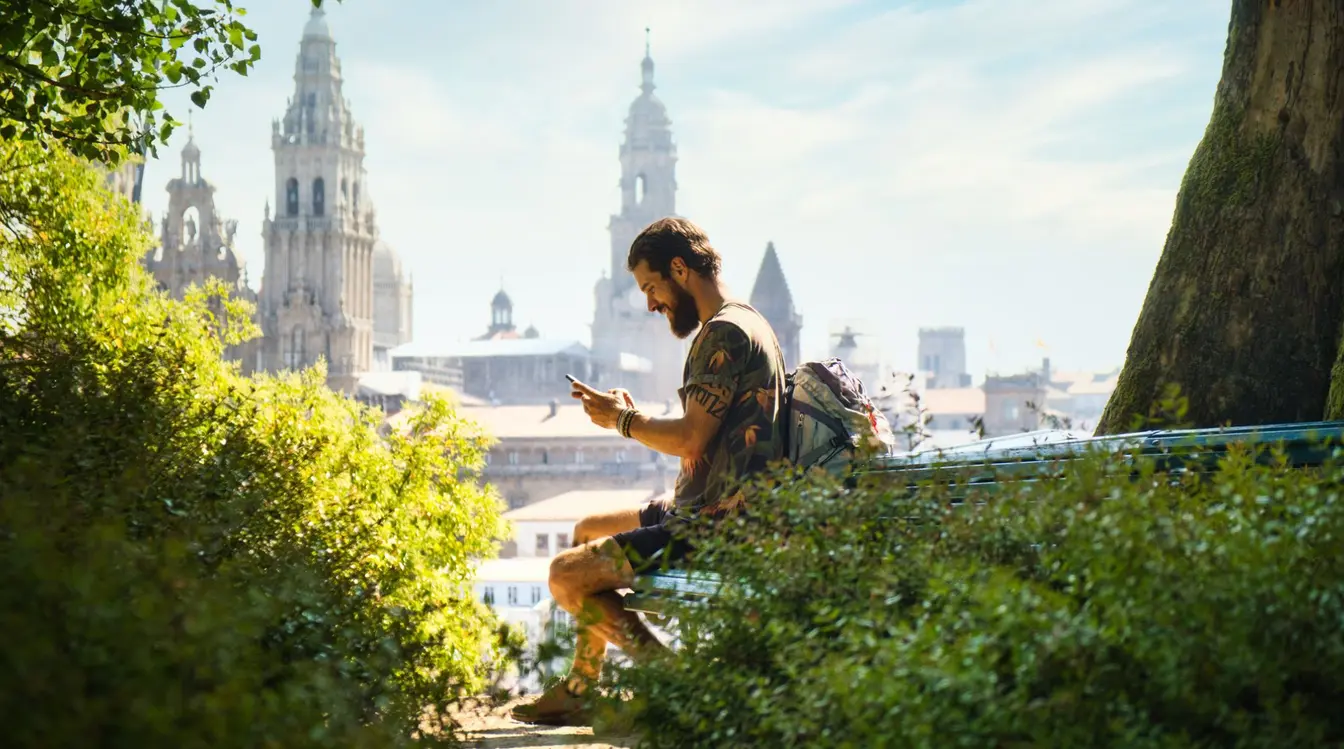Voyageur utilisant son smartphone à Saint-Jacques-de-Compostelle, restant connecté à l'étranger grâce à une eSIM de voyage.