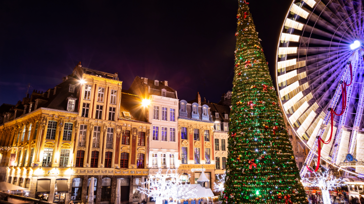A colour image showing a towering conical green Christmas tree overlooking the sandy coloured grand buildings of the French city, Lille. To illustrate a blog post entitled 'Extreme Day Trips: Eurostar Christmas Markets Edition'.