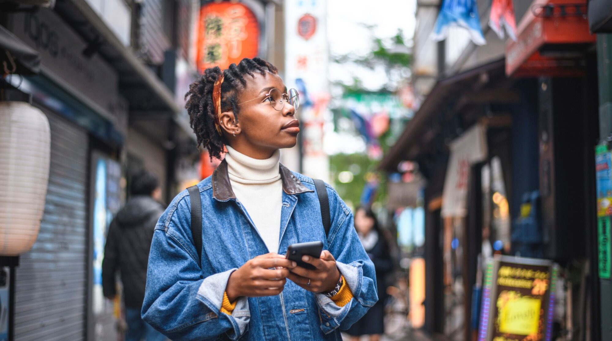 Eine Frau läuft durch eine Gasse in Japan und nutzt Apps, um Läden zu finden