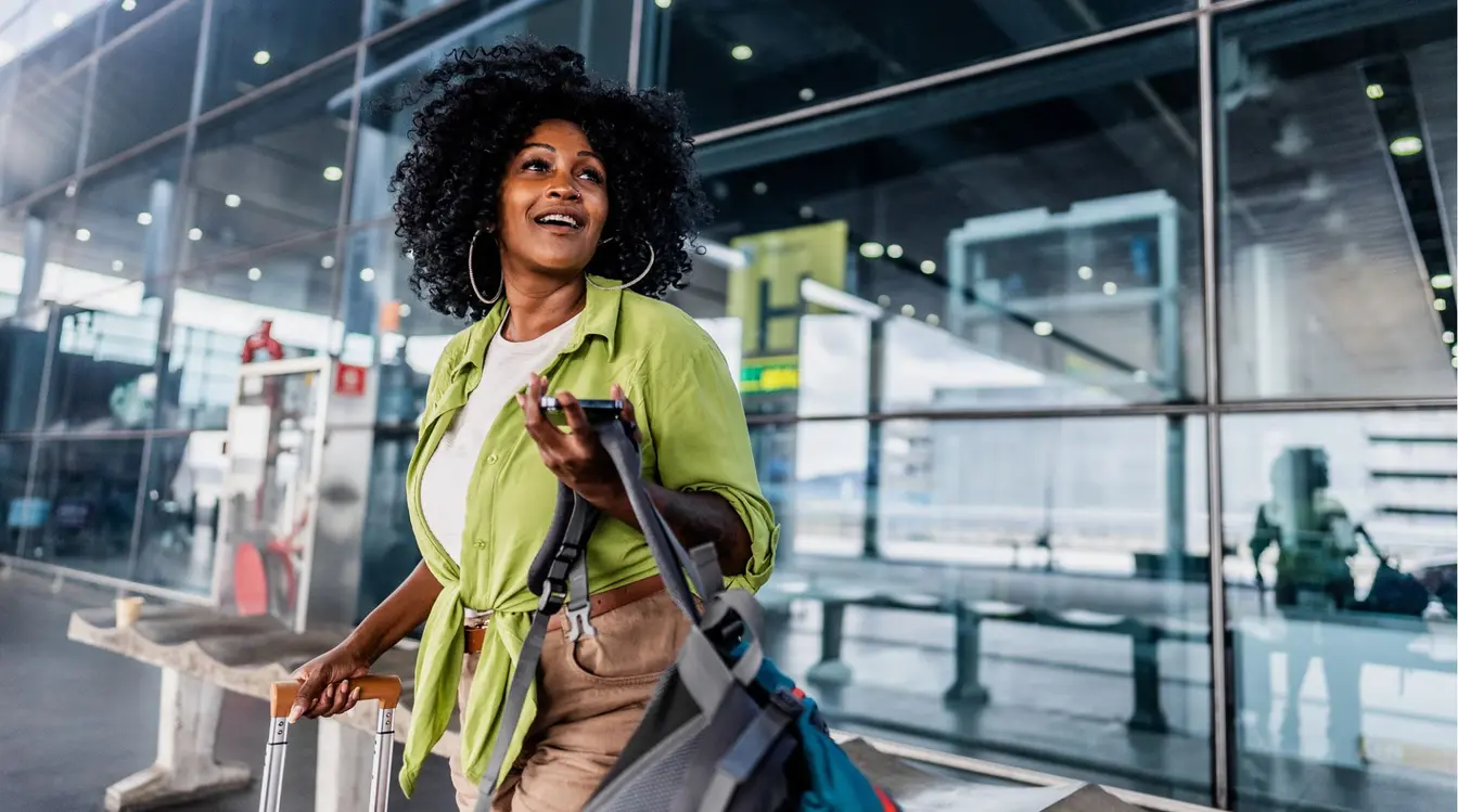 Femme voyageant seule qui arrive à l’aéroport avec ses bagages.