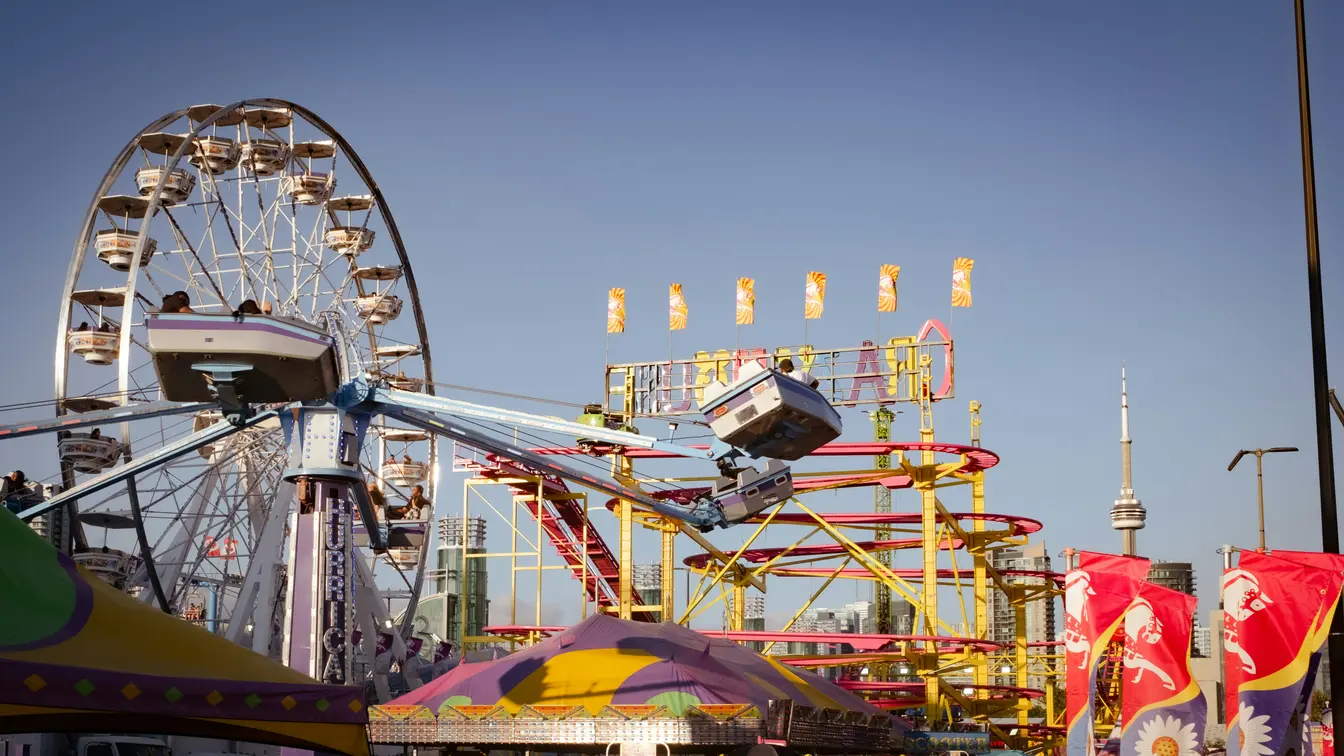 Imagen de las atracciones de la Canadian National Exhibition (CNE) en Toronto, con la Torre CN asomándose al fondo.