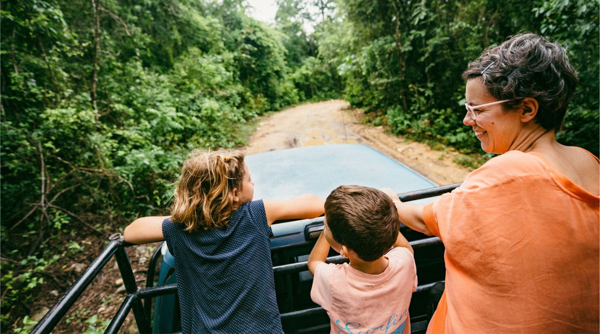 Familia viajando en auto por carretera rodeada de selva en Yucatán, México.