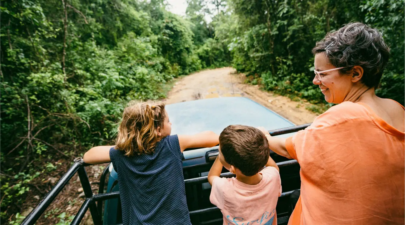 Familia viajando en auto por carretera rodeada de selva en Yucatán, México.