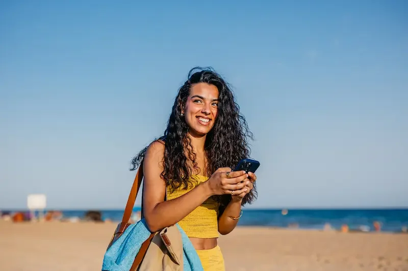 Mujer viajera chateando en su smartphone durante un viaje a la playa.