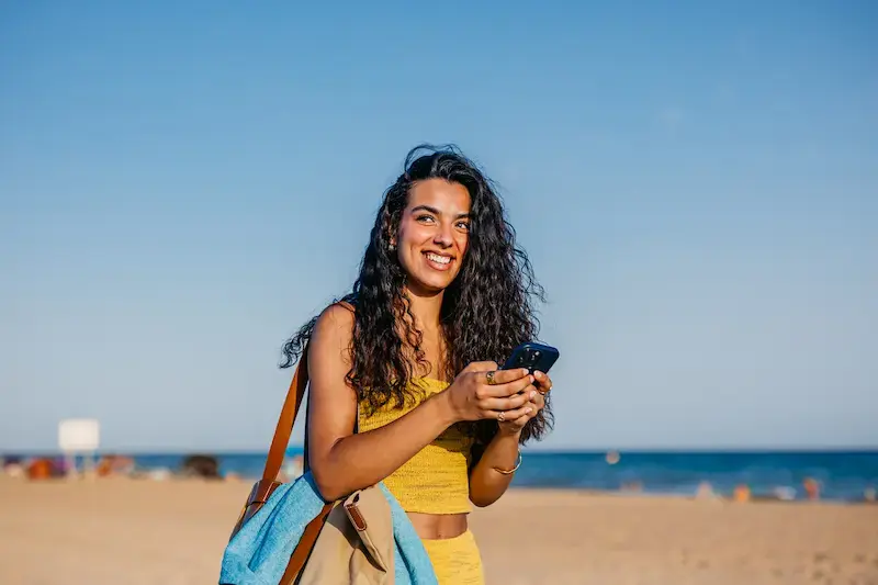 Mujer viajera chateando en su smartphone durante un viaje a la playa.