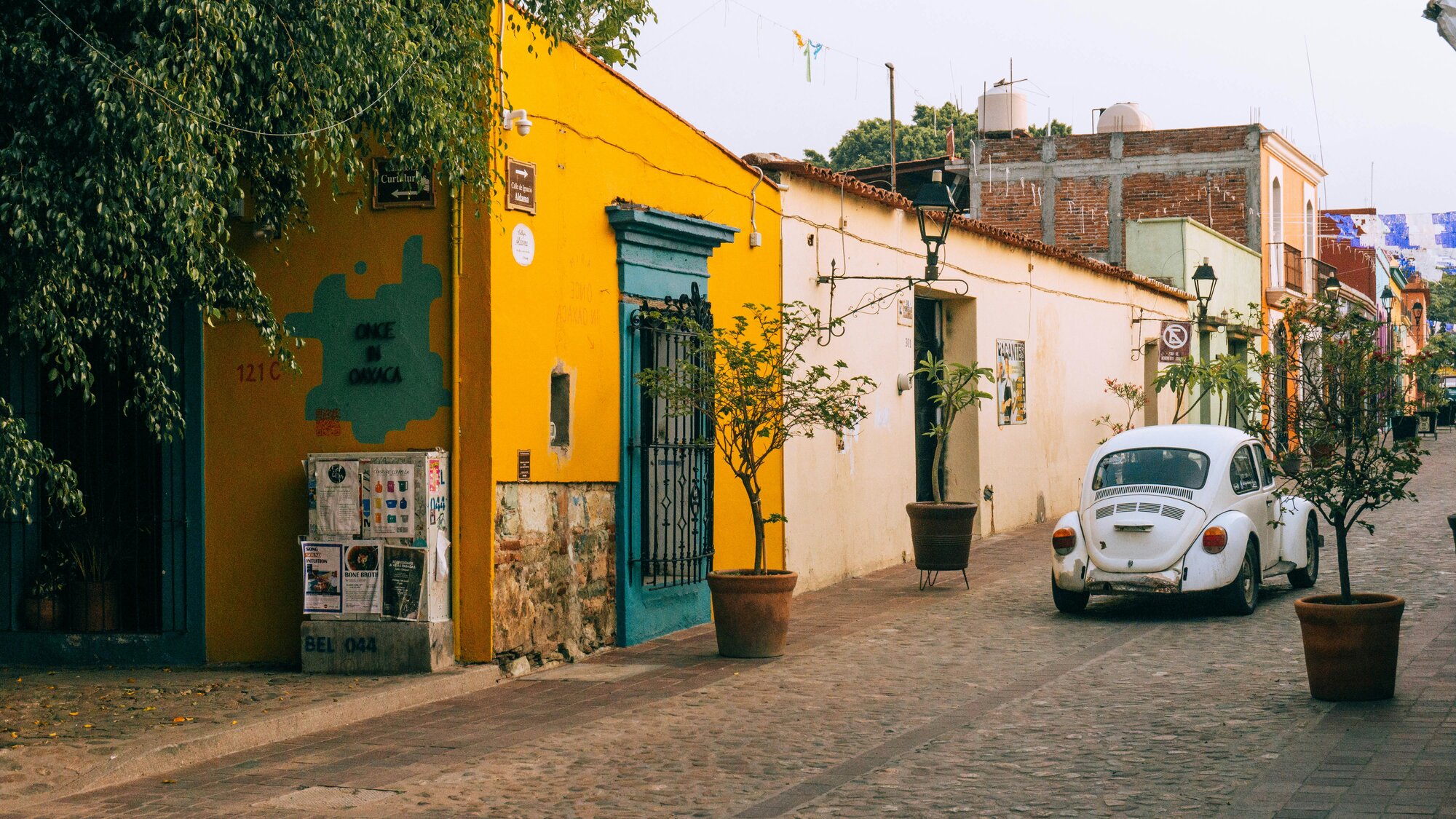 Imagen de una calle empedrada con fachadas coloniales de colores vivos para ilustrar cómo celebran Día de Muertos en Oaxaca