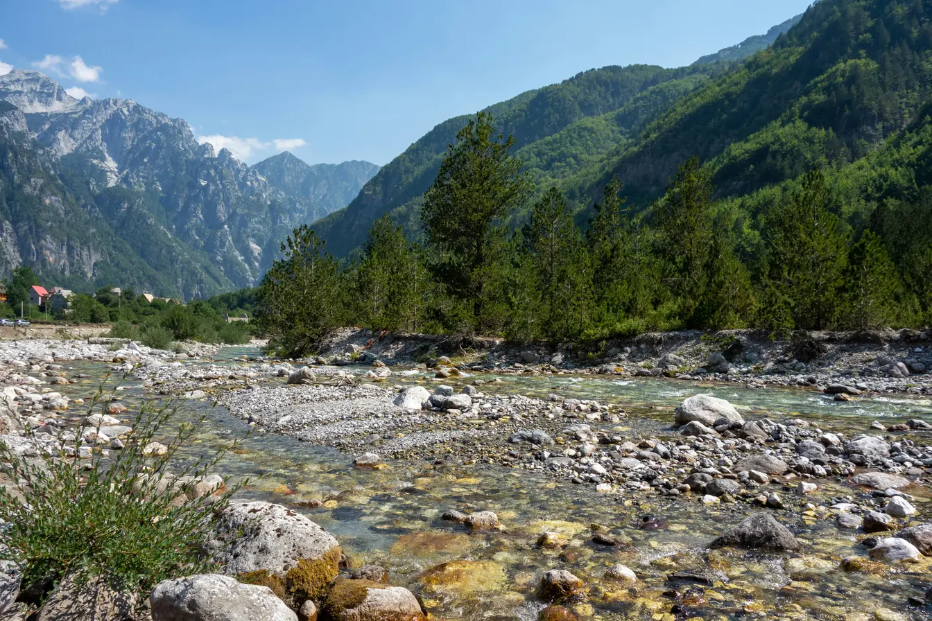 Paesaggio alpino con fiume per chi si chiede dove andare in vacanza a settembre