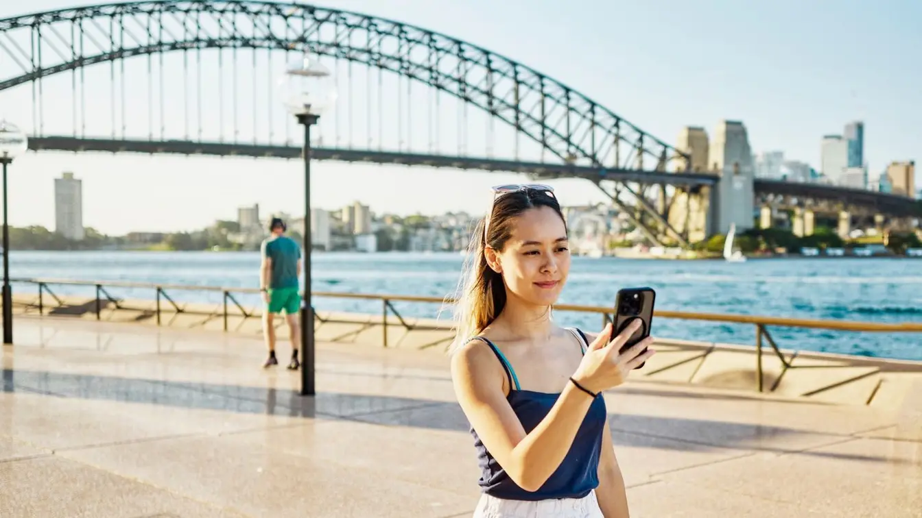 Voyageuse utilisant son téléphone portable pour envoyer un e-mail pendant son séjour en Australie.