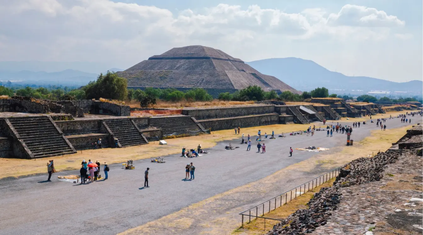 Calzada de los Muertos en Teotihuacán con la Pirámide del Sol al fondo y visitantes caminando