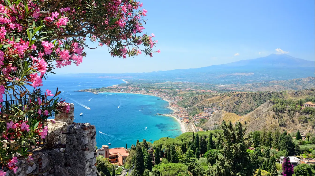 Vue sur Taormine en Sicile, avec le théâtre antique, la mer Ionienne et l'Etna en arrière-plan.