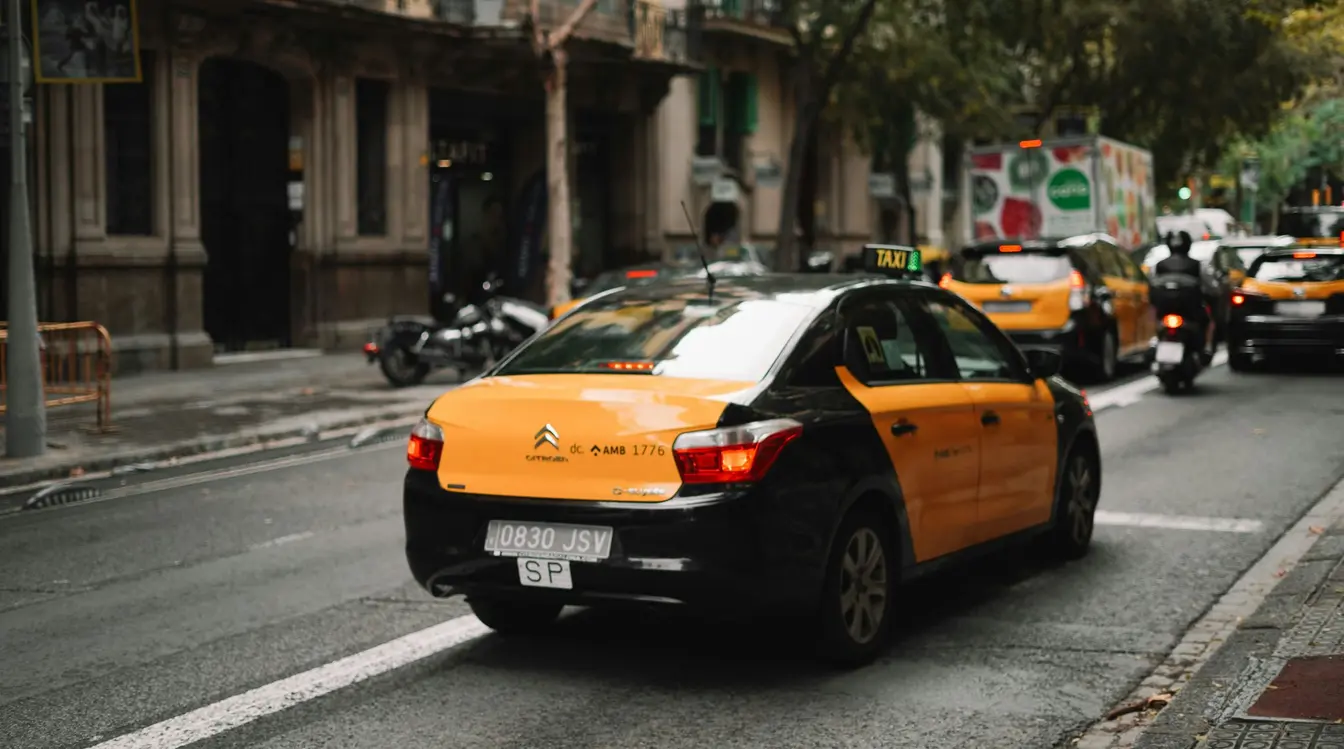 Black and yellow taxi driving down a city street in Barcelona, Spain.