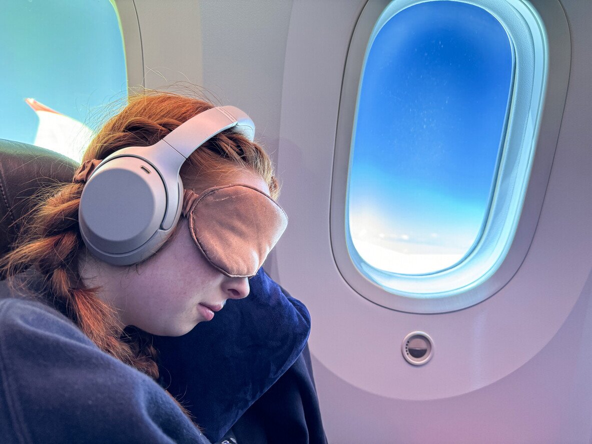 Woman sitting in an airplane wearing an eye mask