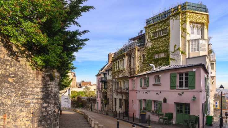 A photograph of a hill in Montmartre,Paris, with the famous cafe at the top, Maison Rose, a building in pink, to illustrate a blog entitled Extreme Day Trips from London to Europe.