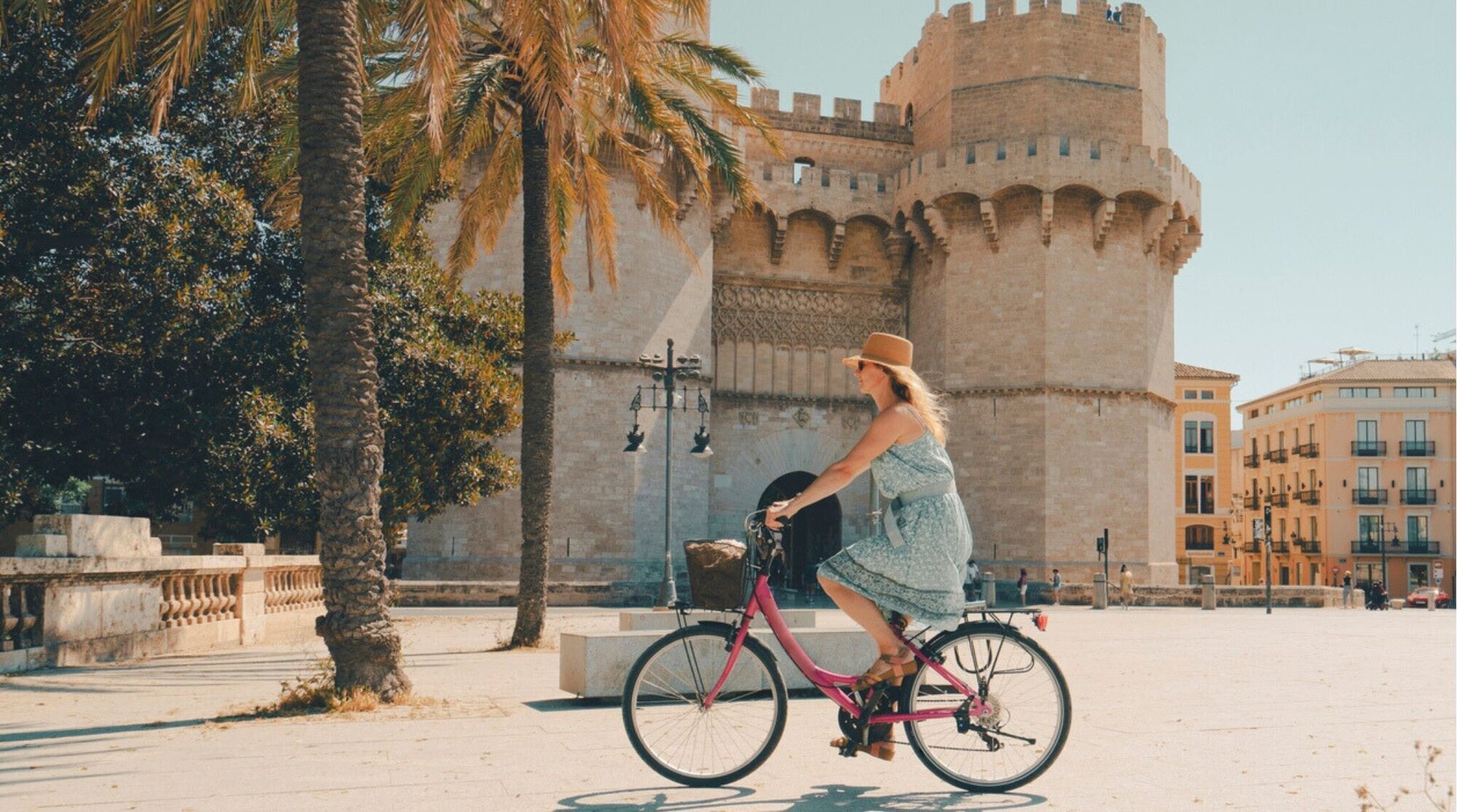 Mulher andando de bicicleta pelo Portão Torres de Serranos, em Valência, Espanha.