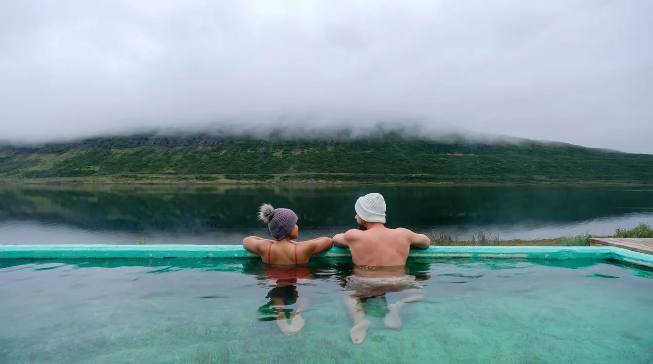 Couple se relaxant dans une source chaude géothermique au cœur des paysages volcaniques d'Islande.