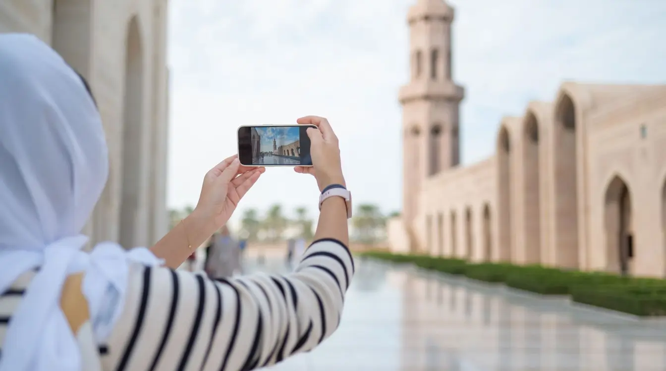 Donna che fotografa la Grande Moschea del Sultano Qaboos a Muscat, in Oman, utilizzando lo smartphone durante il viaggio.
