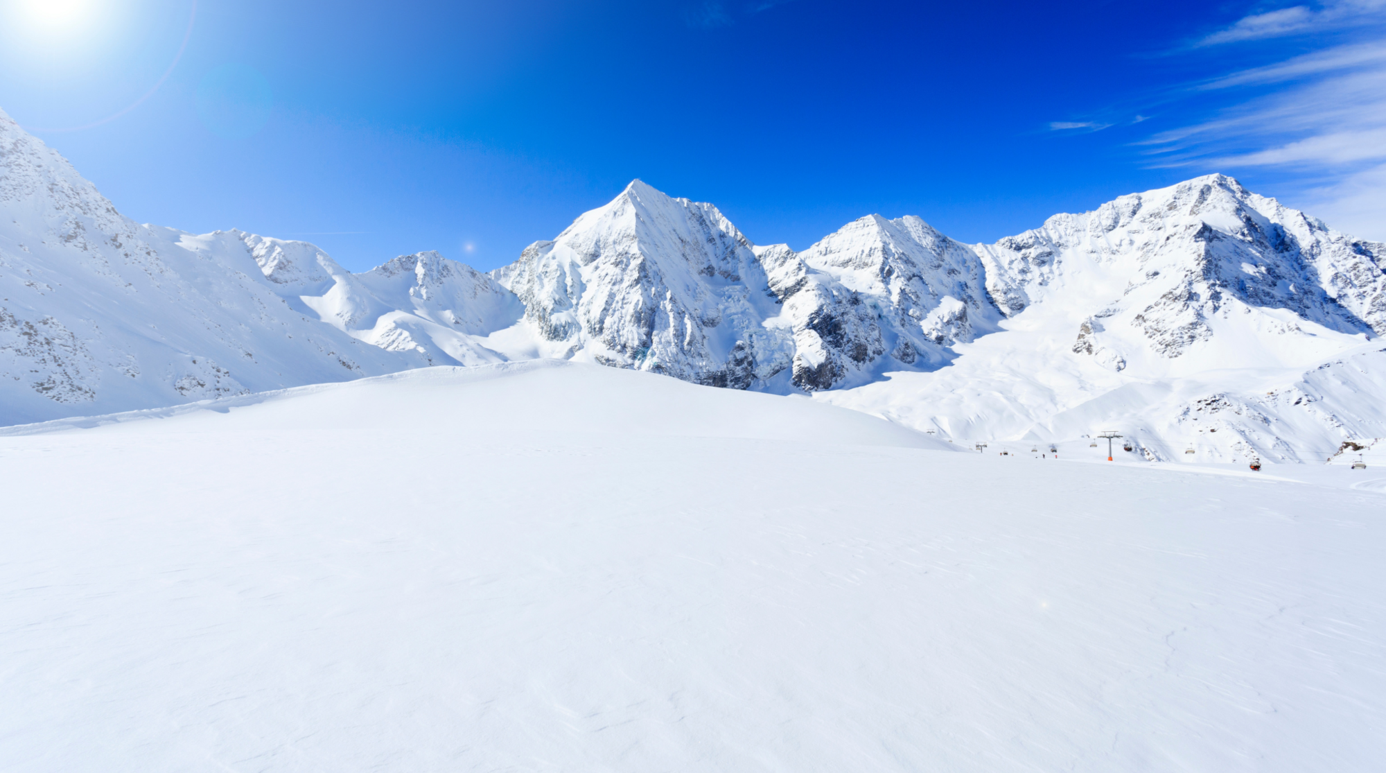 Panorama invernale di montagne innevate con cielo limpido, scenario ideale per una vacanza sulla neve in Europa lontano dalle mete affollate.