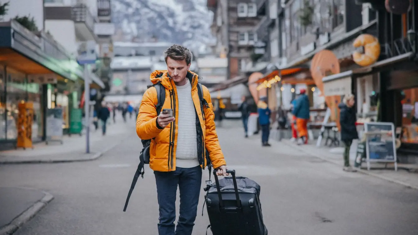 Homme utilisant son smartphone pour trouver l'adresse de son hébergement pendant un voyage en Suisse.