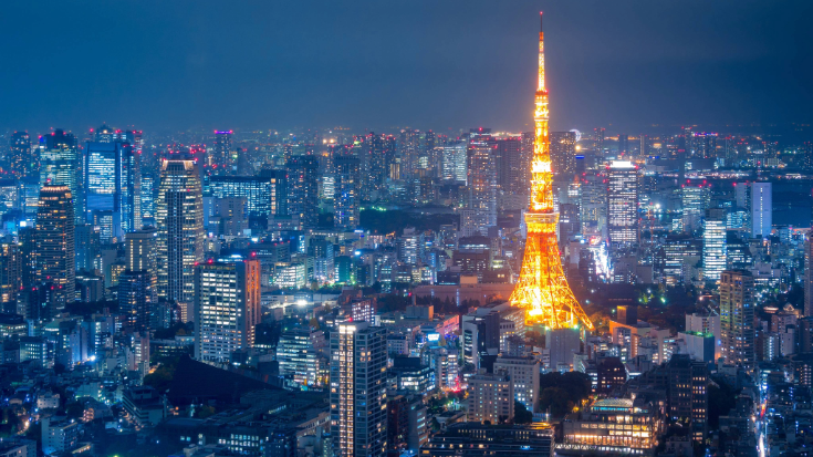 Tokyo Tower glowing bright orange against the night sky, surrounded by neon skyscrapers and buzzing city lights, a must-see view for Tokyo Game Show attendees exploring Tokyo nightlife.