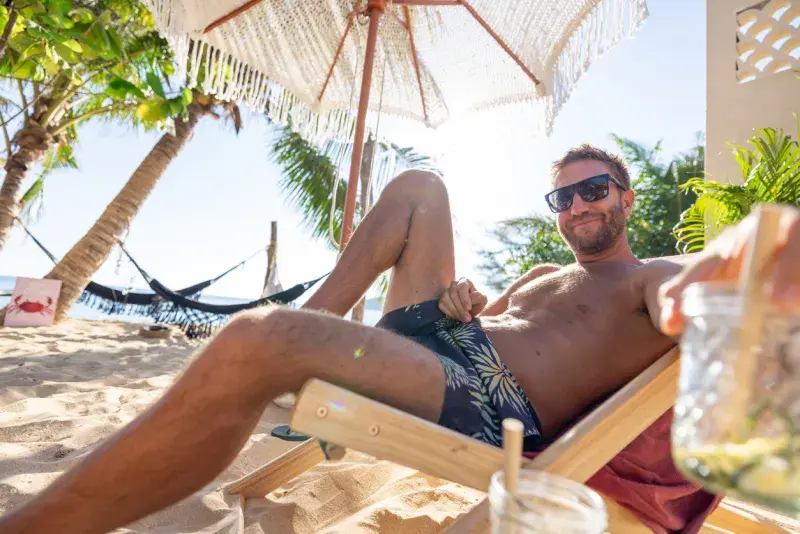 Turista relajado en silla de playa en Cancún con eSIM activa, sin preocupaciones por la conectividad