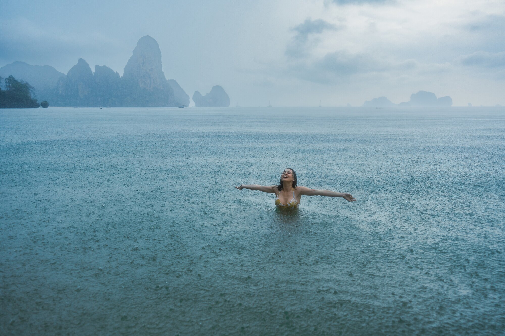 Frau, die im Regen im Meer schwimmt