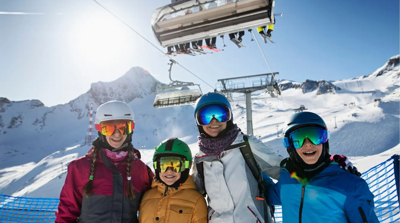  Familia con cascos y gafas de esquí en una estación, junto a un remonte; día soleado en las montañas de Andorra.]