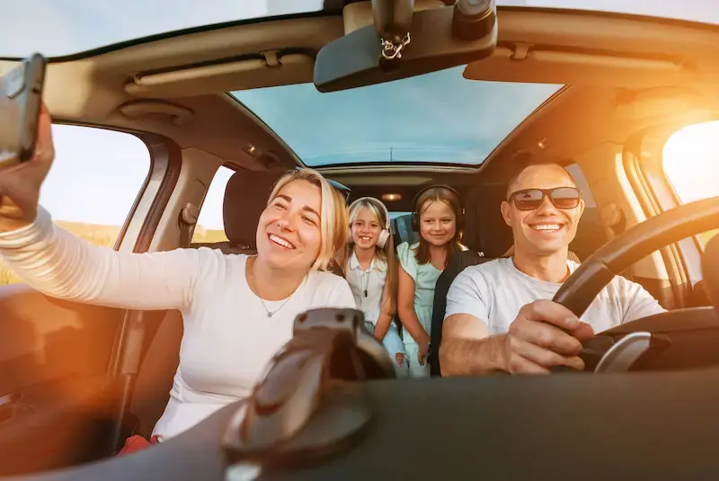 車内でスマートフォンを使って自撮りをする4人家族。