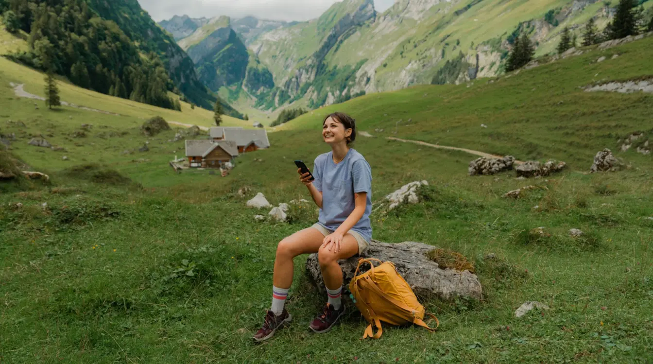 Frau mit Smartphone während einer Wanderung in den Schweizer Alpen im Sommer