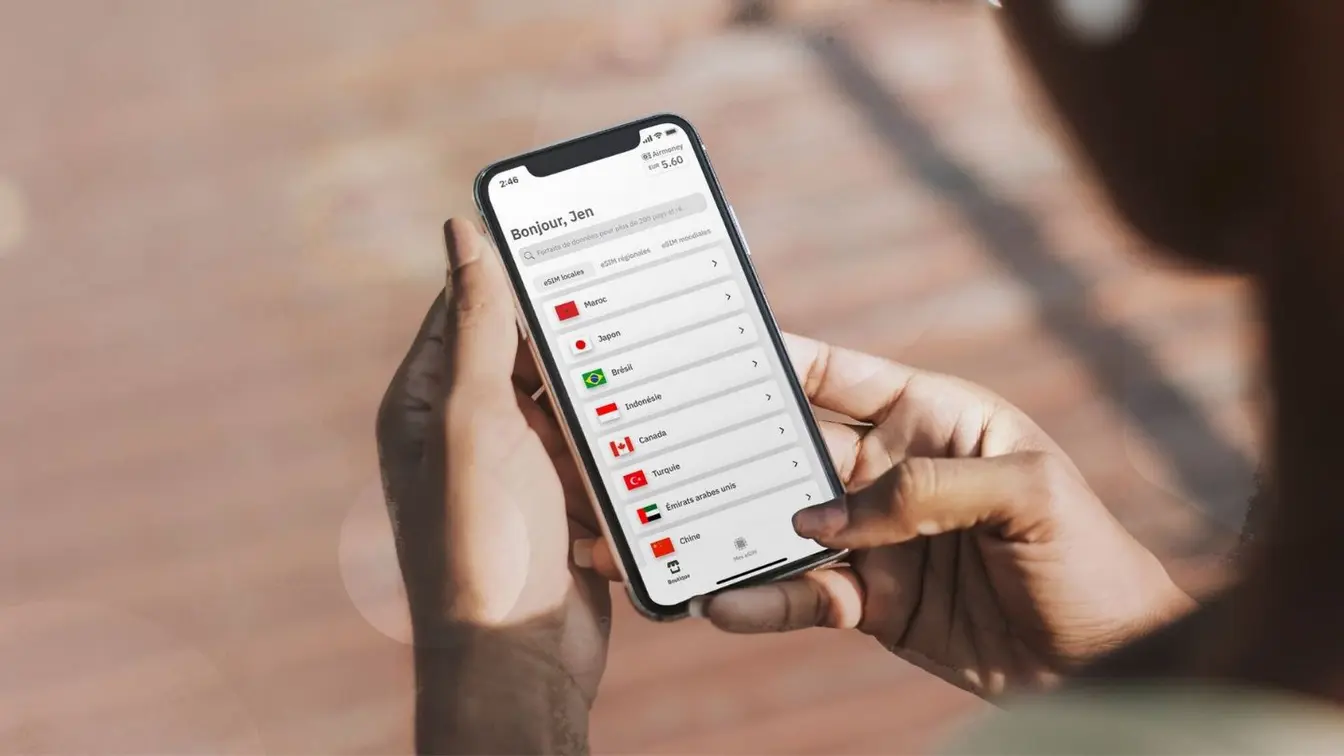 Voyageur utilisant l’application Airalo sur son smartphone pour choisir un forfait eSIM à l’étranger.