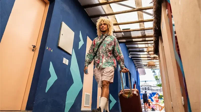 Turista caminando por el pasillo de un hotel con una maleta mientras llega a su destino