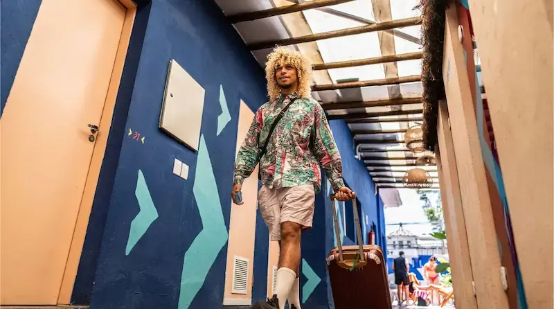 Turista caminando por el pasillo de un hotel con una maleta mientras llega a su destino