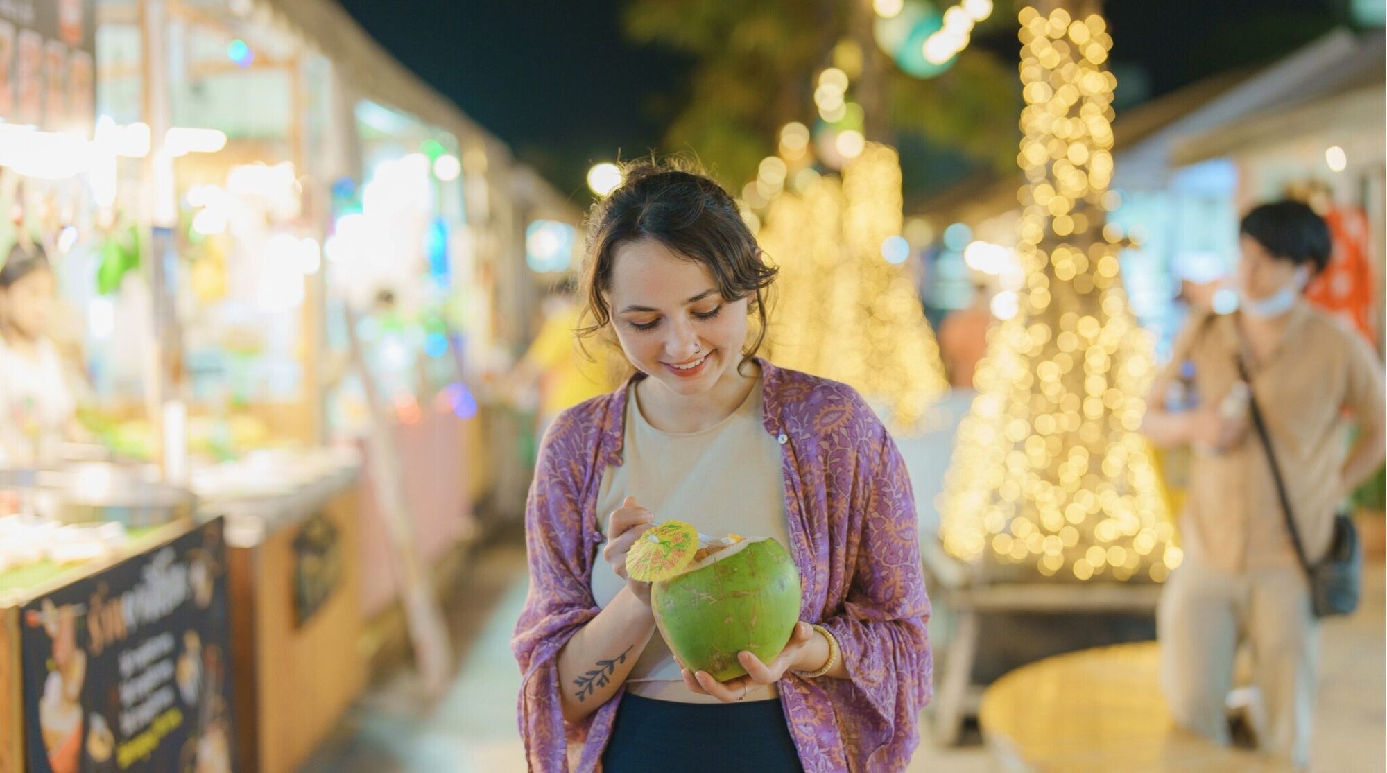 Mulher saboreando sorvete de coco em um mercado noturno natalino em Bangkok, Tailândia