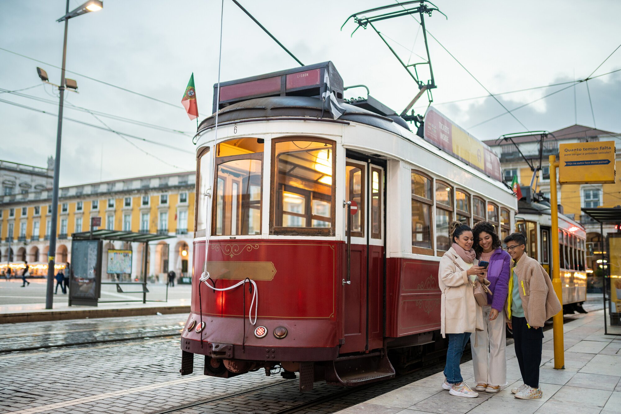 Friends on their phone near a tram in Lisbon