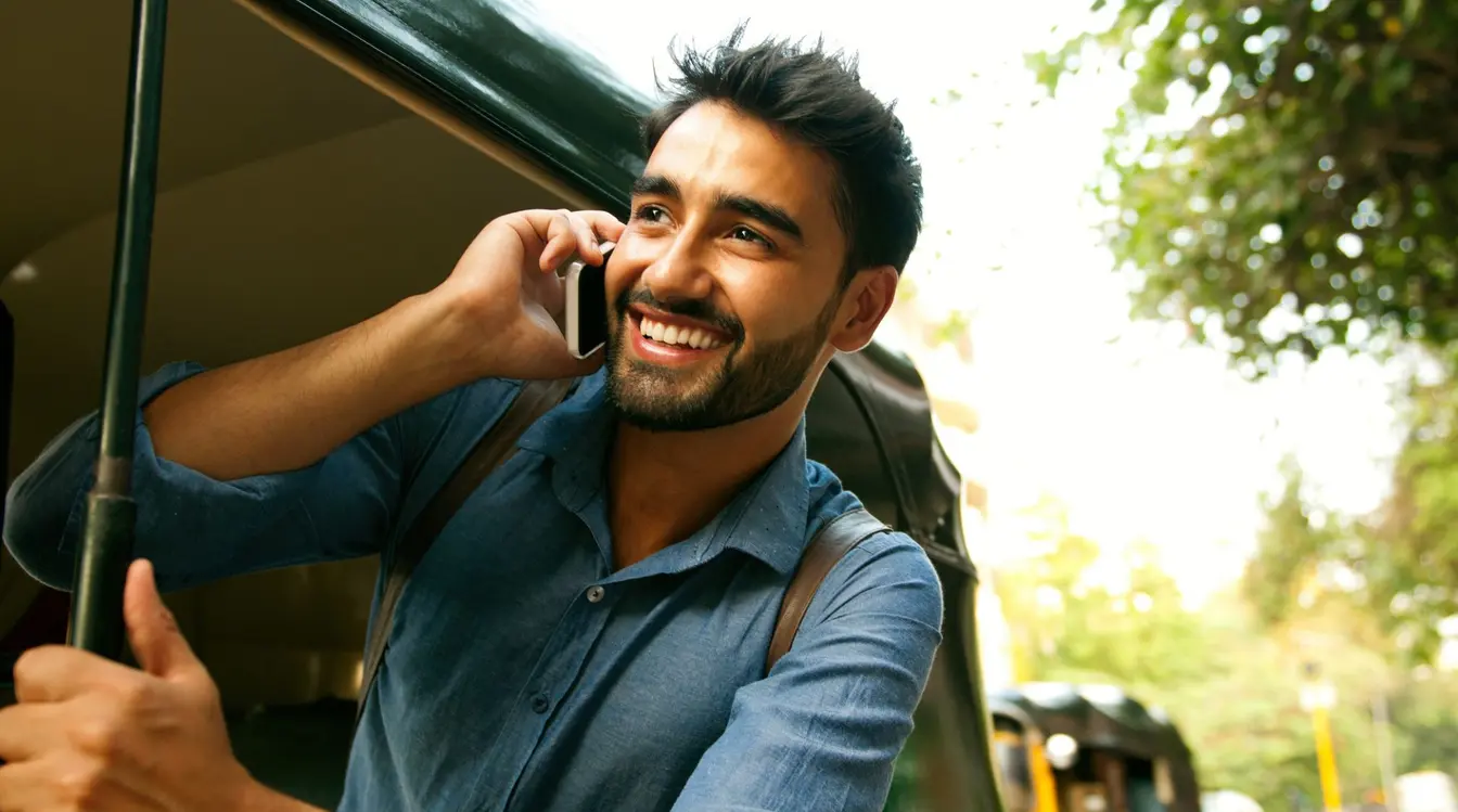 Ein Mann mit SIM-Karte fährt in Indien in einem Auto mit und lächelt