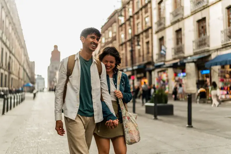 Pareja de turistas caminando por una calle del centro de Ciudad de México con edificios históricos al fondo.