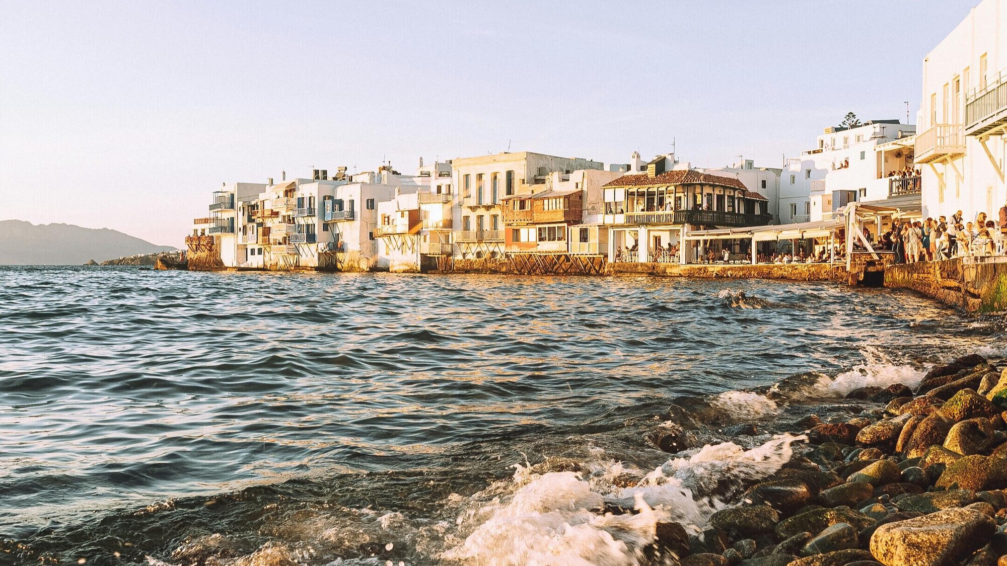 Charming white and cream buildings lining the Greek coastline at sunset